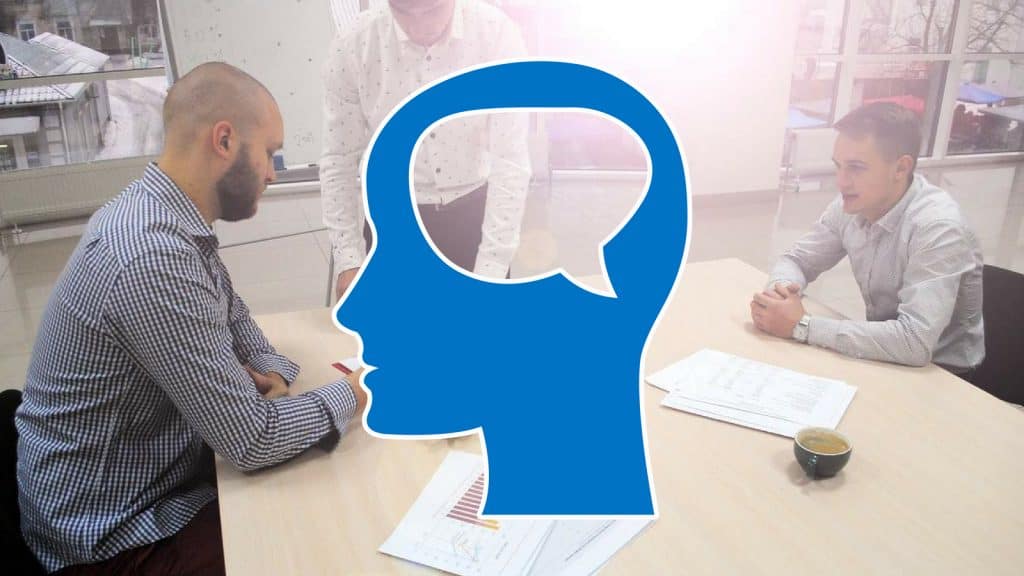 Geschäftsleute am Meetingtisch hinter Symbol eines nachdenkenden Kopfes