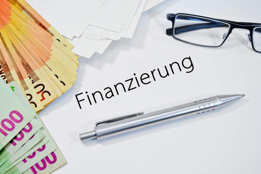 MBI-Finanzierung: Bargeld, eine Brille und ein Kugelschreiber auf dem Verhandlungstisch