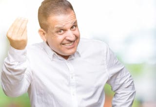 Stark lächelnder Mann, der die Hand zur italienisches Geste für bene hebt