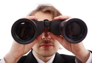 Ein Mann im Anzug schaut durch ein Fernglas