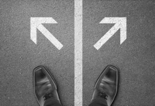 Blick auf ein paar Füße an einem Scheideweg stehend