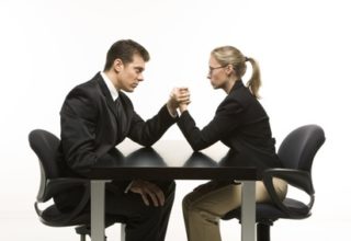 Ein Mann und eine Frau im Anzug veranstalten eine Arm-Drück Wettbewerb